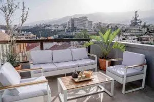 Balkon mit weißen Loungemöbeln und Stadtansicht.
