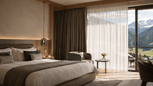 Modernes Hotelzimmer mit großen Fenstern, Store und Dimout-Vorhängen für Hitzeschutz und thermischen Komfort